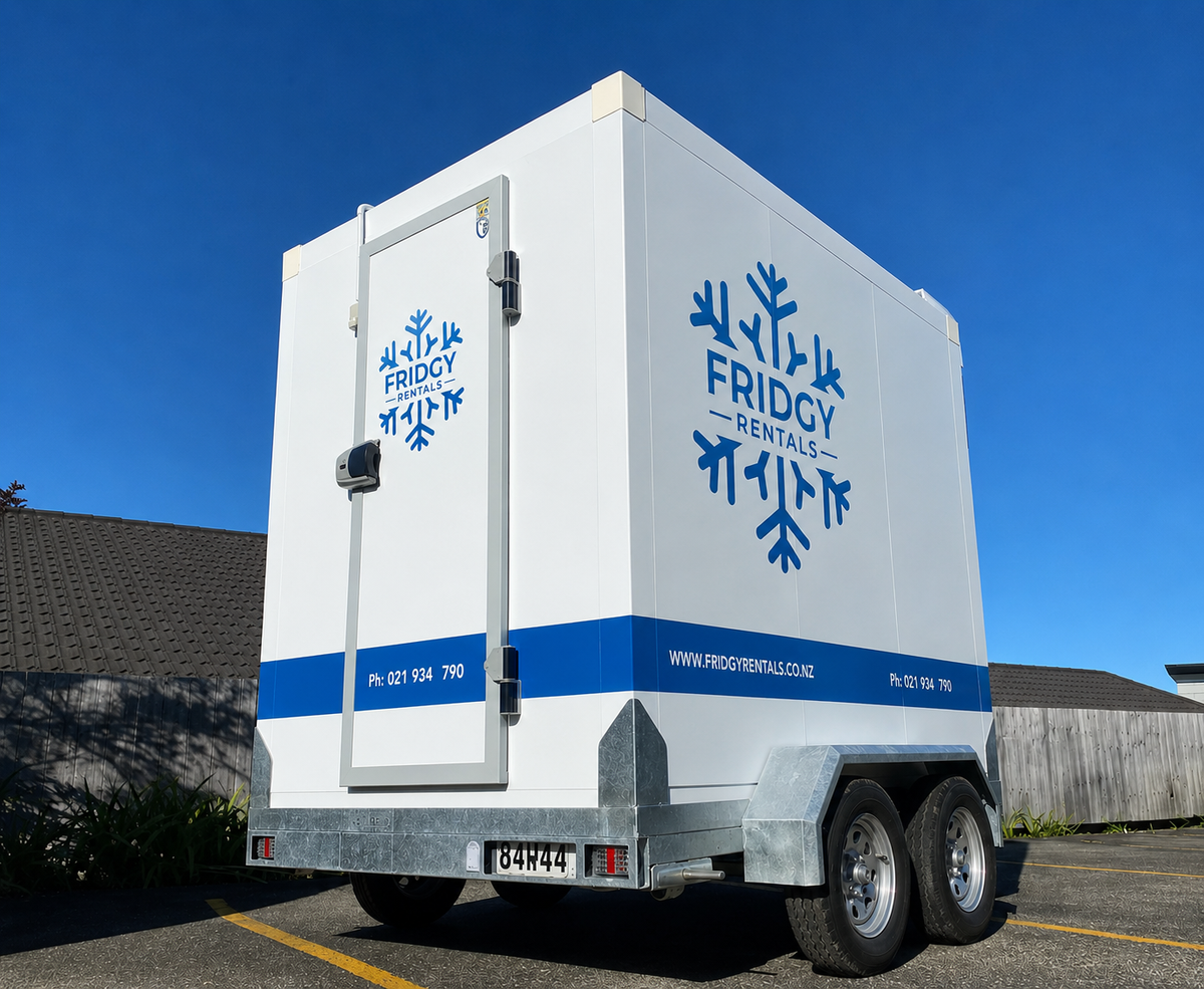 Extra large twin-axle Fridgy Rentals trailer from the front corner, showing the walk-in door and snowflake logo