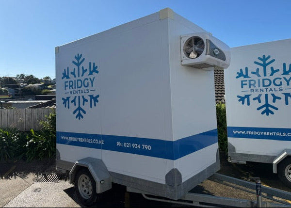 Large Fridgy Rentals trailer, white with a blue stripe and the snowflake logo, parked outdoors